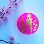 Bright neon pink round bath fizzy with gold glitter in a random splatter effect on top half