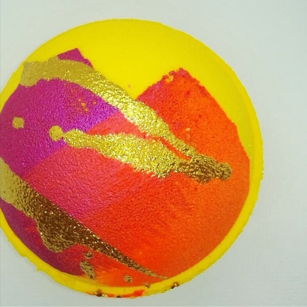 Bright yellow, round bath bomb decorated with  autumn colours of pink, orange and gold