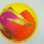 Bright yellow, round bath bomb decorated with  autumn colours of pink, orange and gold
